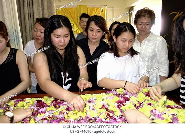 Relatives putting flowers into the coffin. Sarawakian chinese funeral ceremony. Malaysia