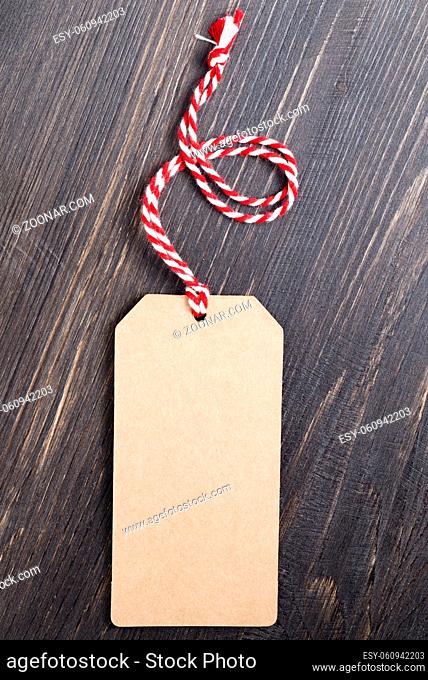 Recycled paper tag with a red and white rope on a black board background