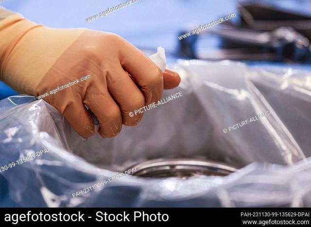 PRODUCTION - 29 November 2023, Schleswig-Holstein, Rendsburg: A surgical assistant wrings out a cloth during an operation in the Schön Klinik's operating center