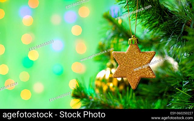 Christmas decoration gold star on a branch of a christmas tree, sparkling shiny background copy space design for postcard