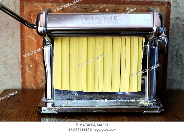 Fresh tagliatelle in a pasta machine