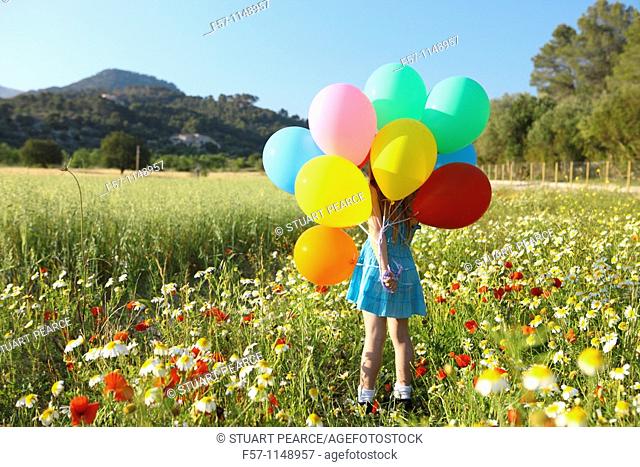 Girl in meadow with balloons