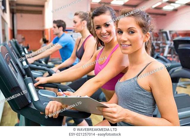 Gym Instructor and woman in the gym smiling on the exercise bicycle