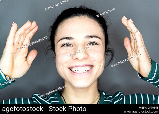 Cheerful woman gesturing against gray background