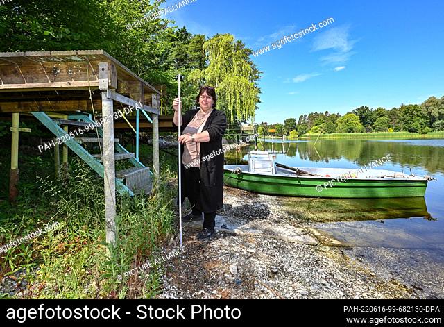 15 June 2022, Brandenburg, Grünheide: Eike-Gina Nixdorf, fisherman and owner of Lake Elsen, stands with a measuring stick next to a jetty on the dry shore