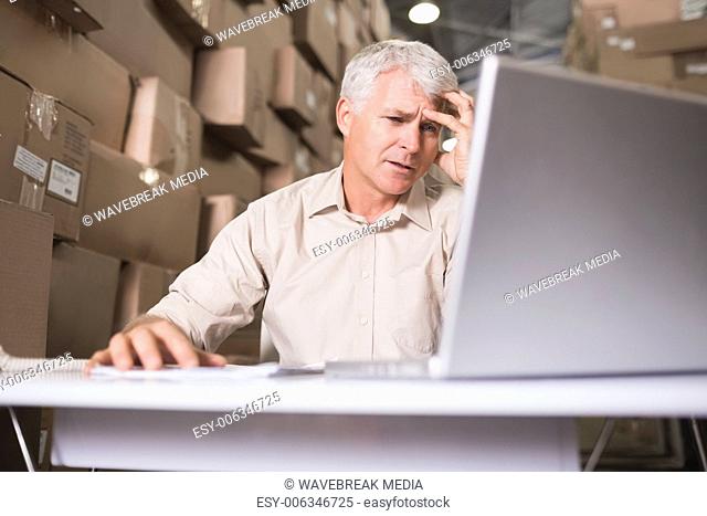 Worried warehouse manager with laptop