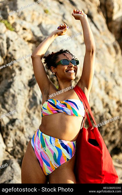 Carefree woman with arms raised standing at beach