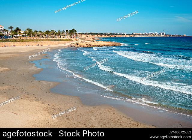 Empty Flamenco beach, Orihuela Costa, surf of Mediterranean Sea, sunny winter day. Province of Alicante, Costa Blanca, Spain