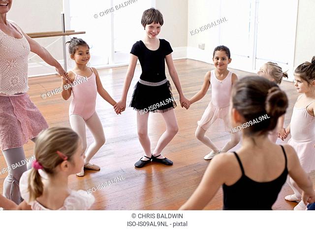 Children and teacher in a circle practicing ballet in ballet school
