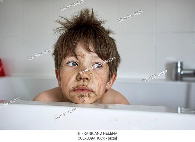 Boy with muddy face, sitting in bath