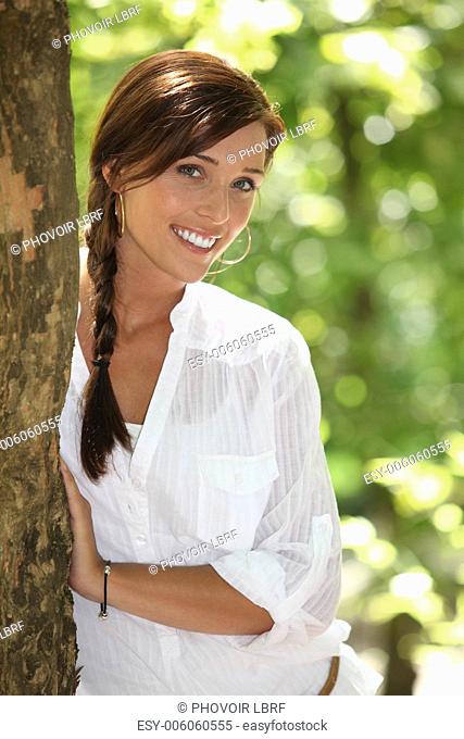 Woman peeking out from behind a tree