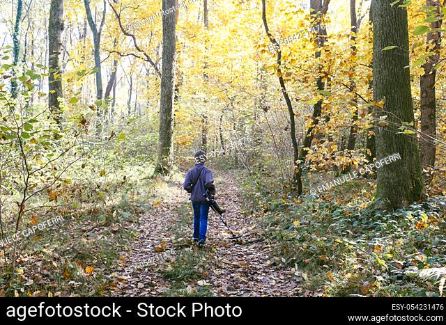 Child with metal detector in the forest in autumn