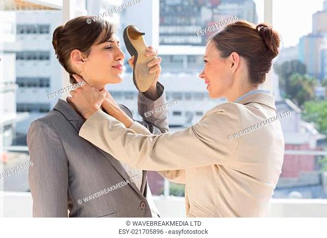 Businesswoman strangling another who is defending with her shoe