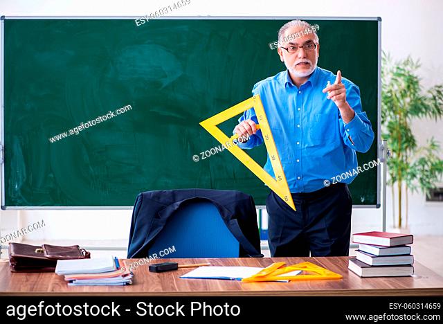 Senior male geometry teacher holding triangle