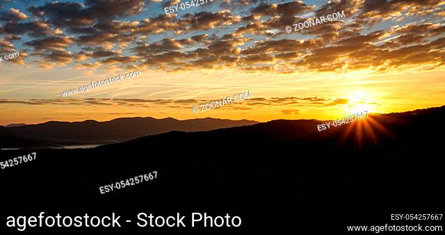 sunrise over mountain silhouette in the Appalachian mountains of western North Carolina in late fall under an expressive blue and cloudy sky