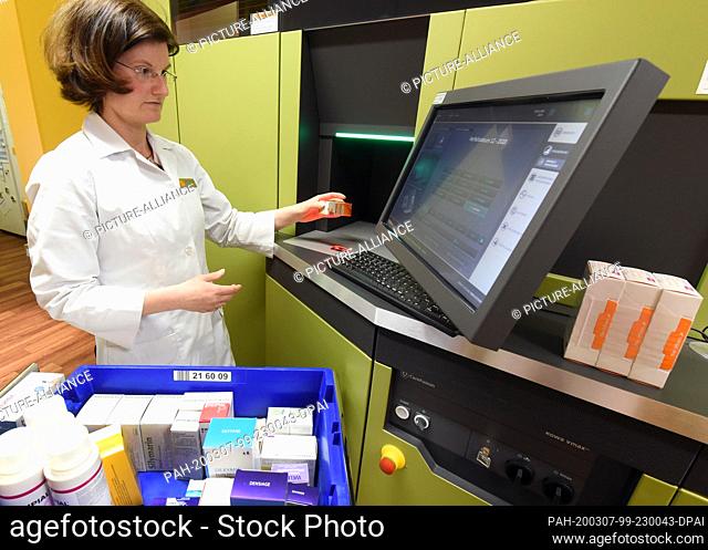06 March 2020, Saxony, Leipzig: A pharmacist in the rose pharmacy in the Auwald forest uses a computer to fill the medicine store where a robot is working