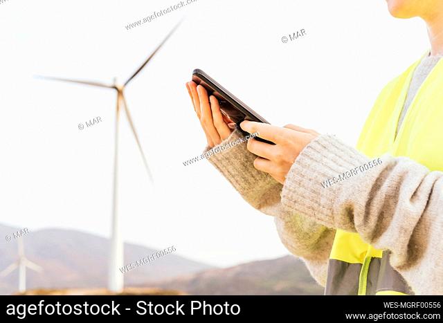Woman using mobile phone at wind farm