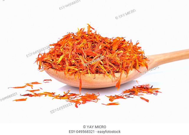 Safflower petals in a spoon on white background