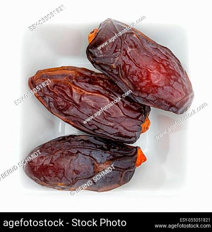 Dried date fruit in a white square bowl in top view