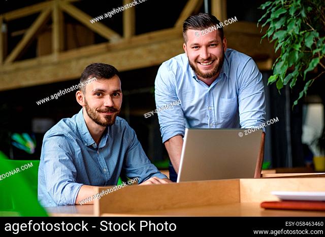 Picture of handsome businessman listening to his colleague or partner concerning ner business system while working on laptop computer in office interior