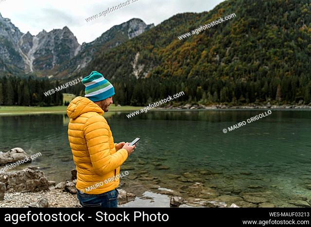 Hiker using smartphone at Laghi di Fusine, Friuli Venezia Giulia, Italy