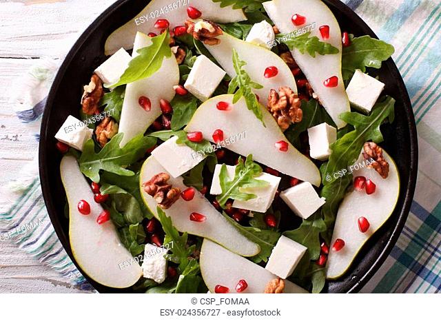 salad with pears, pomegranates and arugula closeup. horizontal top view