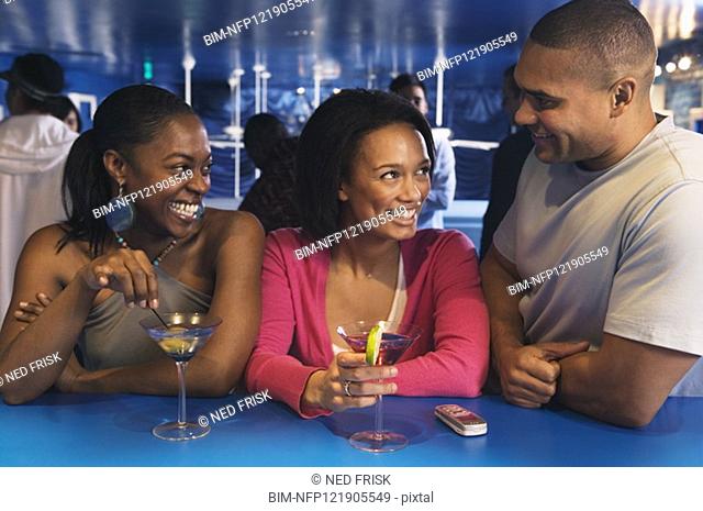 Three African friends laughing at bar