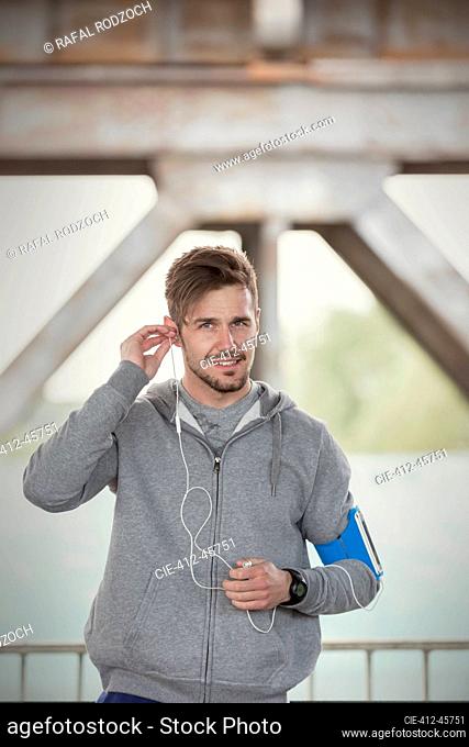 Portrait confident young male runner with headphones and mp3 player arm band