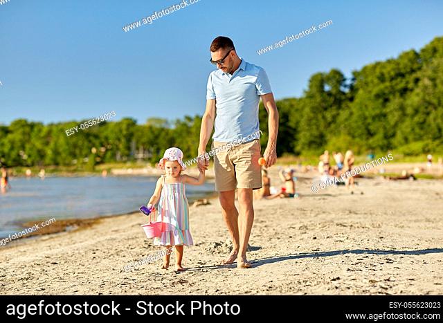 happy father walking with little daughter on beach