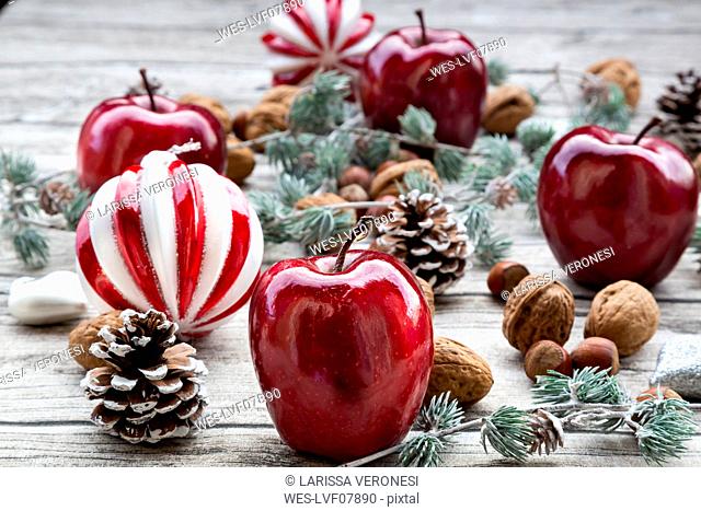 Christmas apples, walnuts, hazelnuts and Christmas decoration on wood