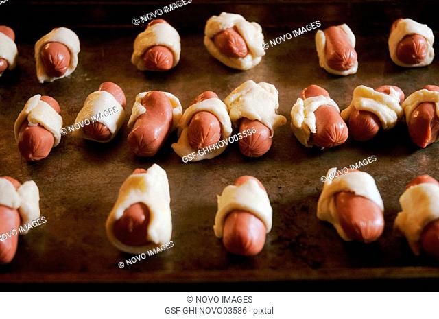 Pigs-in-a-Blanket Miniature Hot Dogs Wrapped in Pastry Dough on Baking Sheet