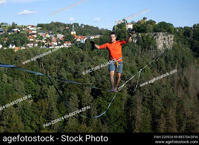 24 September 2022, Saxony, Hohenstein: The slackline runner Gregor Lawrenz runs at the Highline - and family festival on a 360 meter long rope between the...