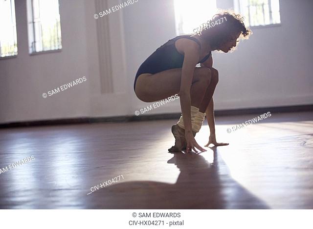 Strong young female dancer stretching toes in dance studio