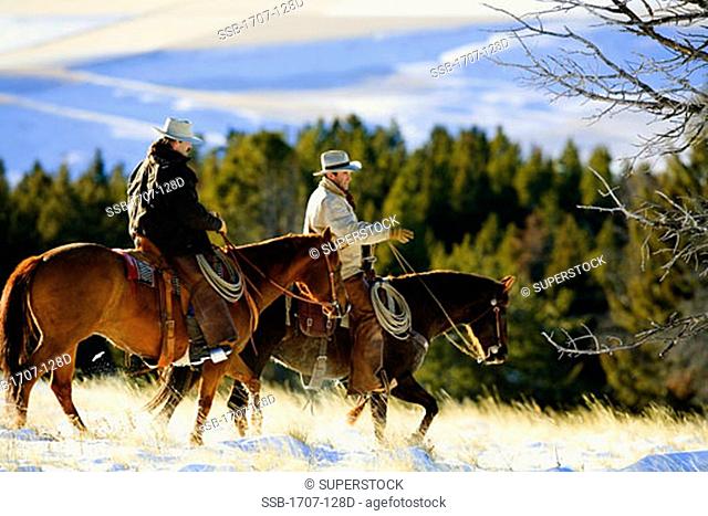 Two men riding horses in a snow covered field