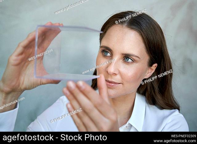 Portrait of confident woman looking at transparant cube