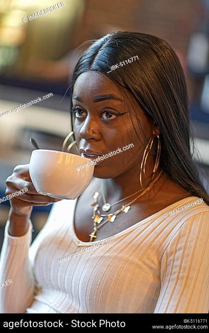 Dark-skinned young woman drinking coffee, Düsseldorf, Germany, Europe