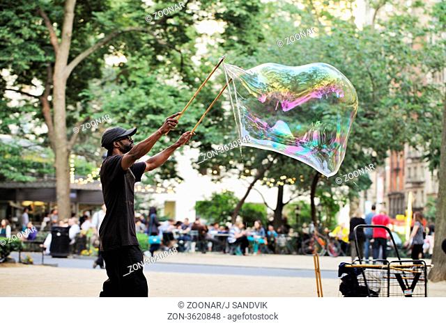 NEW YORK CITY, USA - JUNE 13: Man making big soap bubbles at Madison Square Park, Flatiron District, Manhattan. June 13, 2012 in New York City, USA