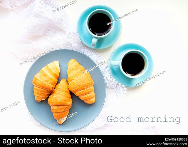 two cups of coffee with croissants on the background of lace inscription good morning