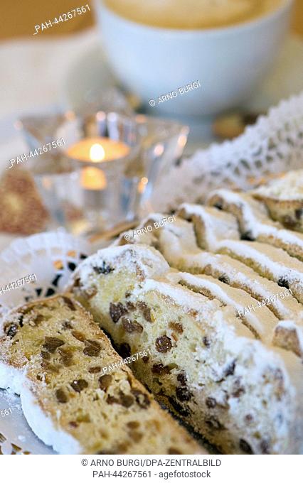 Slices of Dresden Christmas Stollen lie on a plate next to a cup of milky coffee and candles at the confectioner's and cafe Bierbaum in Dresden, Germany