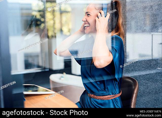 Happy young businesswoman wearing headset in soundproof cabin