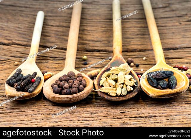 Closeup of four wooden cooking spoons in a row with various exotic spices on a rustic wooden background with copy space