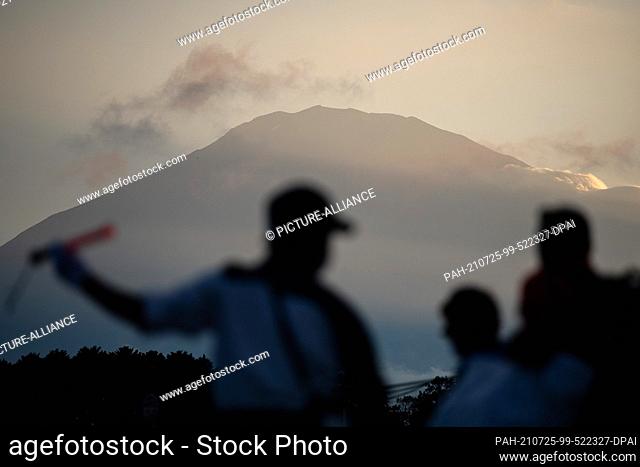25 July 2021, Japan, Oyama: A security guard waves passers-by in front of Mount Fuji. The 2020 Tokyo Olympics will be held from July 23 to Aug