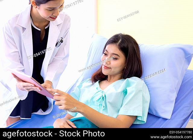 Asian Doctor make routine health check with patient in hospital ward using digital Tablet
