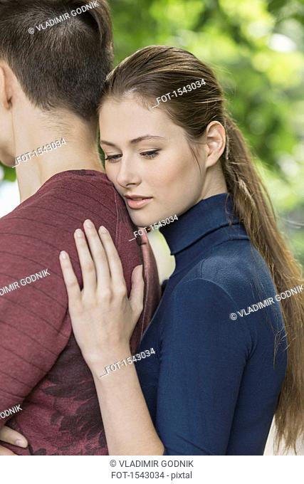 Thoughtful woman leaning on boyfriend's back at park