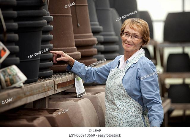 Portrait of a senior woman standing by pots in garden center