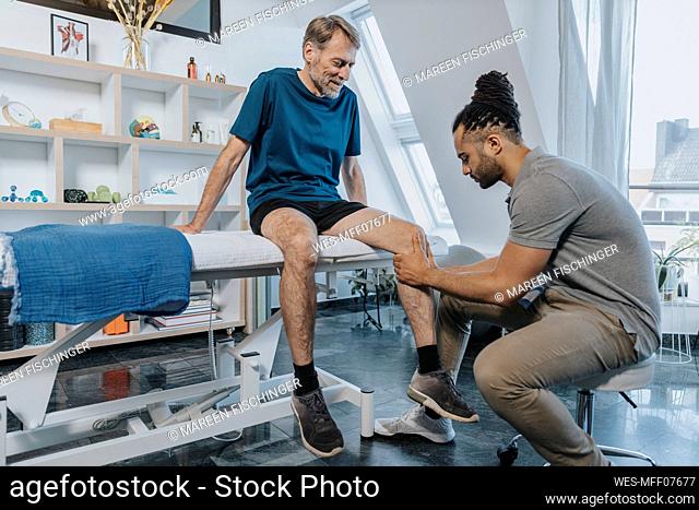 Male physiotherapist checking out knee of patient in practice