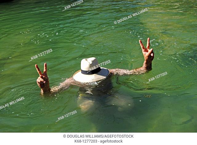 Man wearing a panama hat in the water of a creek