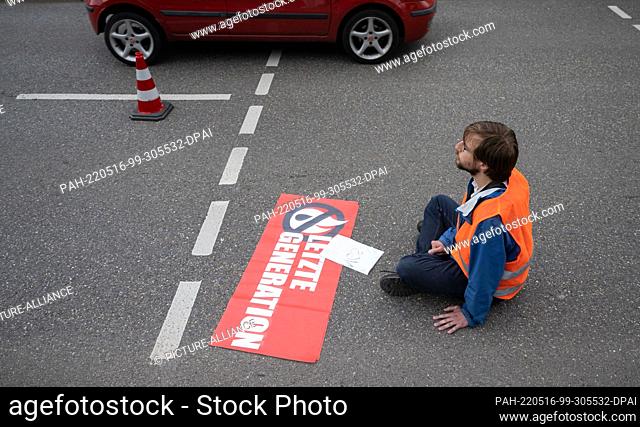 16 May 2022, Baden-Wuerttemberg, Stuttgart: A climate activist from the group ""Uprising of the Last Generation"" blocks a road in Stuttgart
