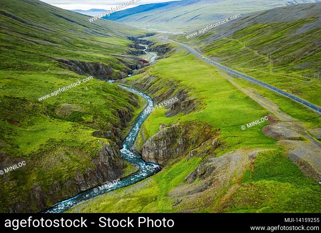 aerial view of remote mountain road and river in the valley at north in iceland, summertime