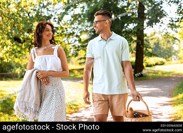 happy couple with picnic basket at summer park